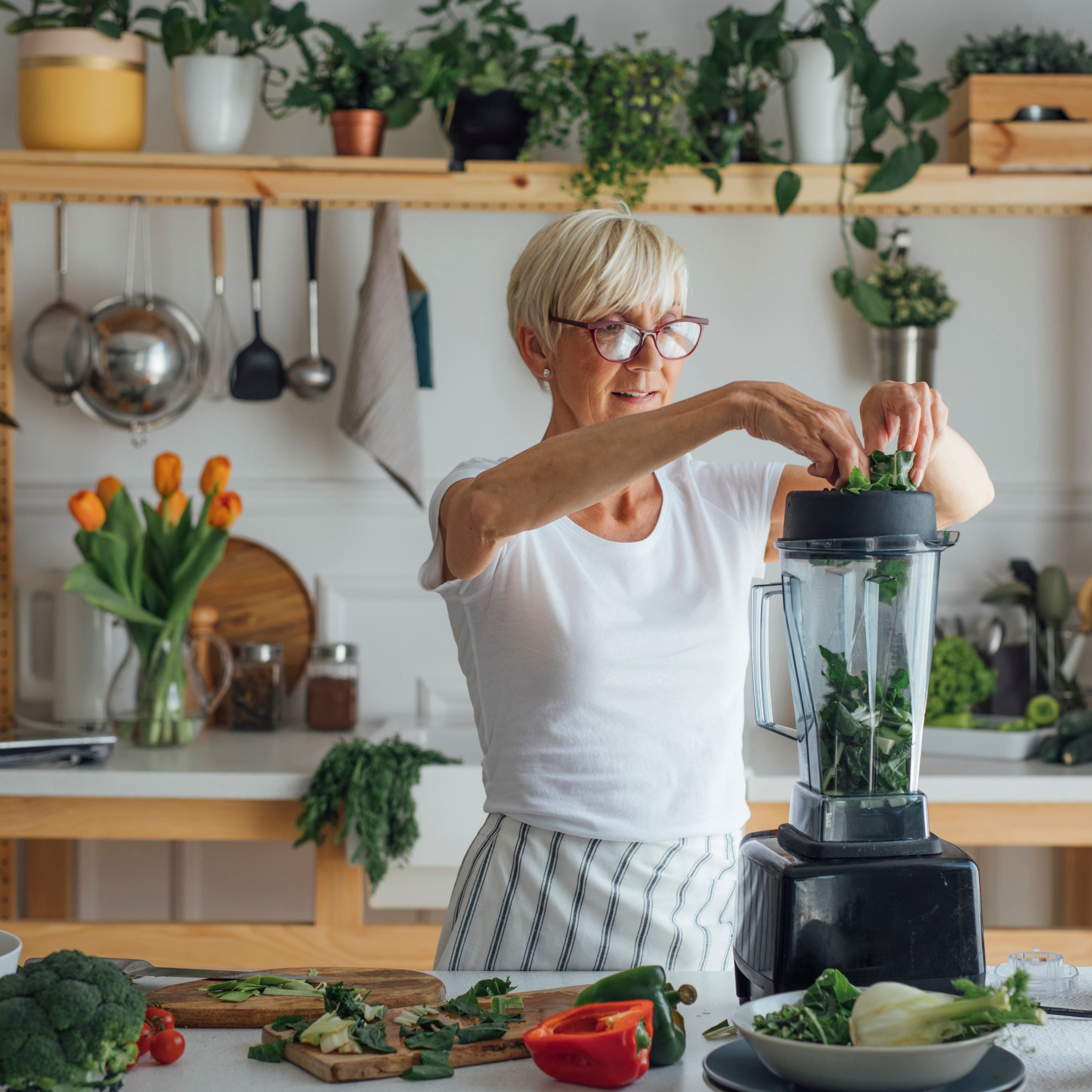 Dame bereitet einen grünen Smoothie im Mixer zu