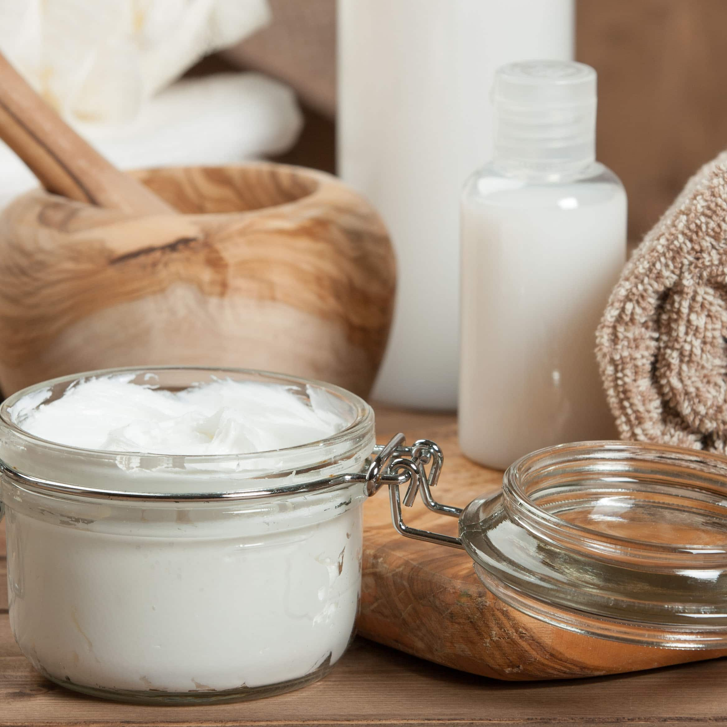 Shampoo in einem Gläschen neben einem Handtuch auf Holzuntergrund