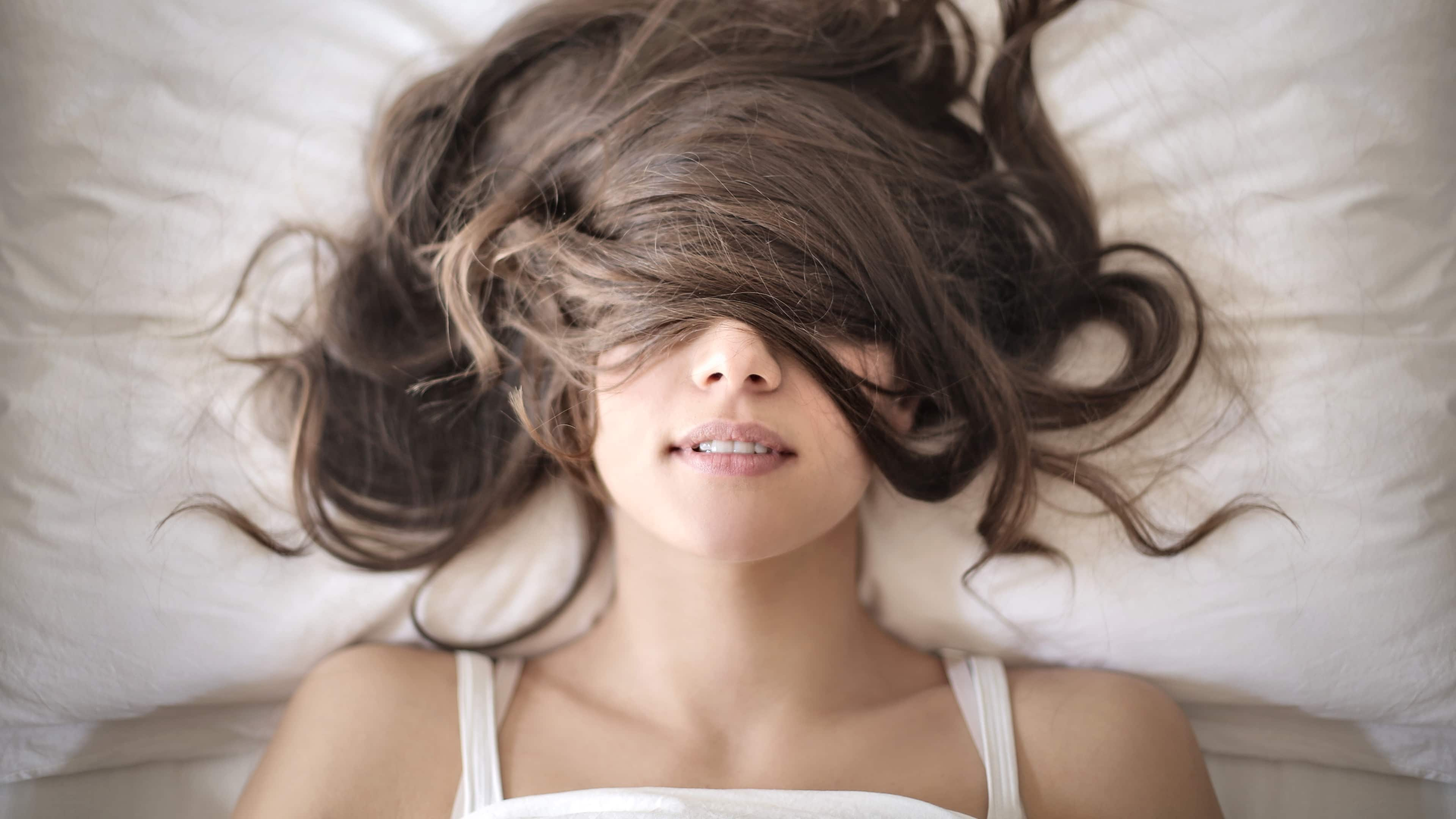 Frau liegt im Bett mit Haaren im Gesicht