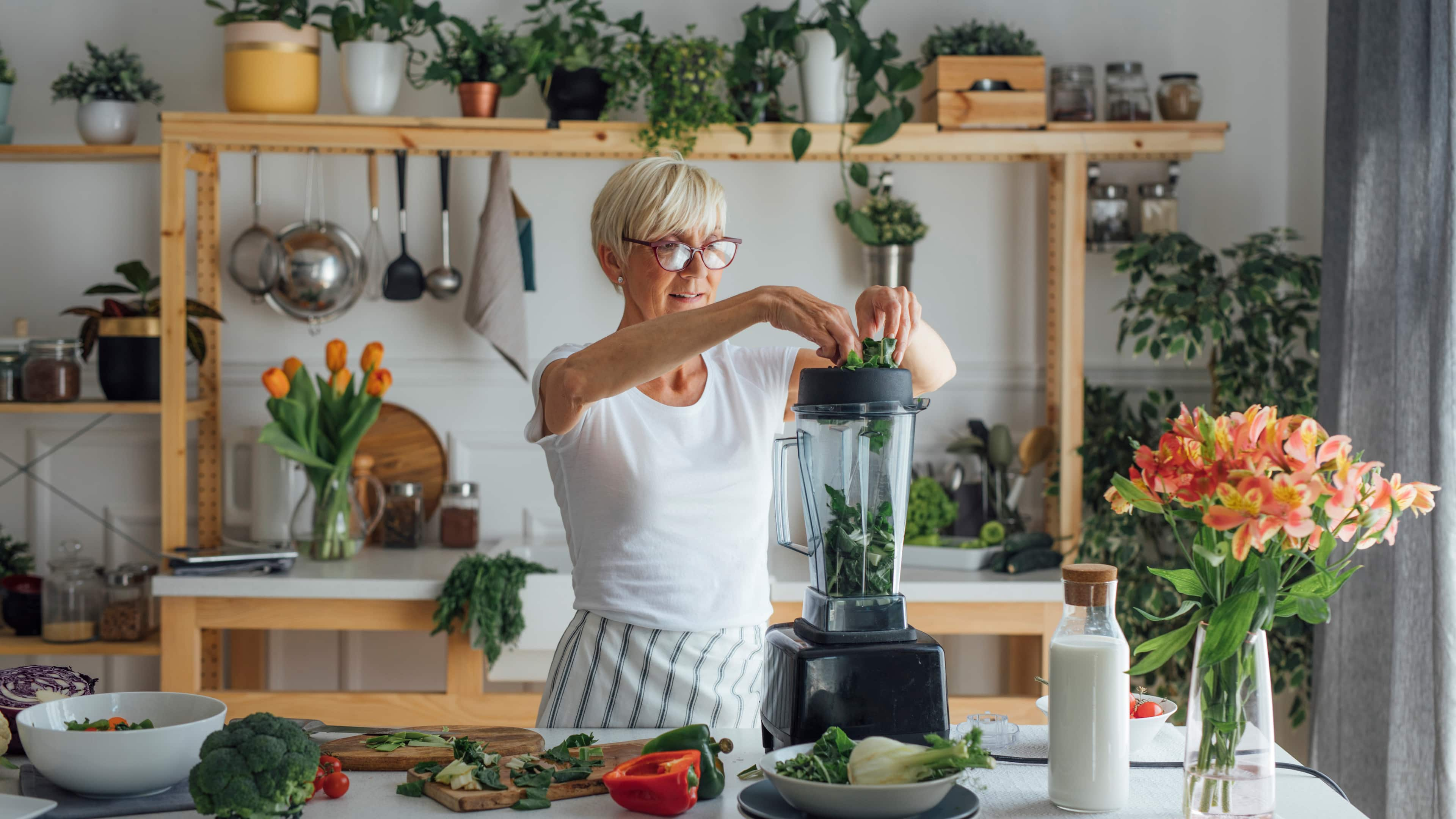 Dame bereitet einen grünen Smoothie im Mixer zu