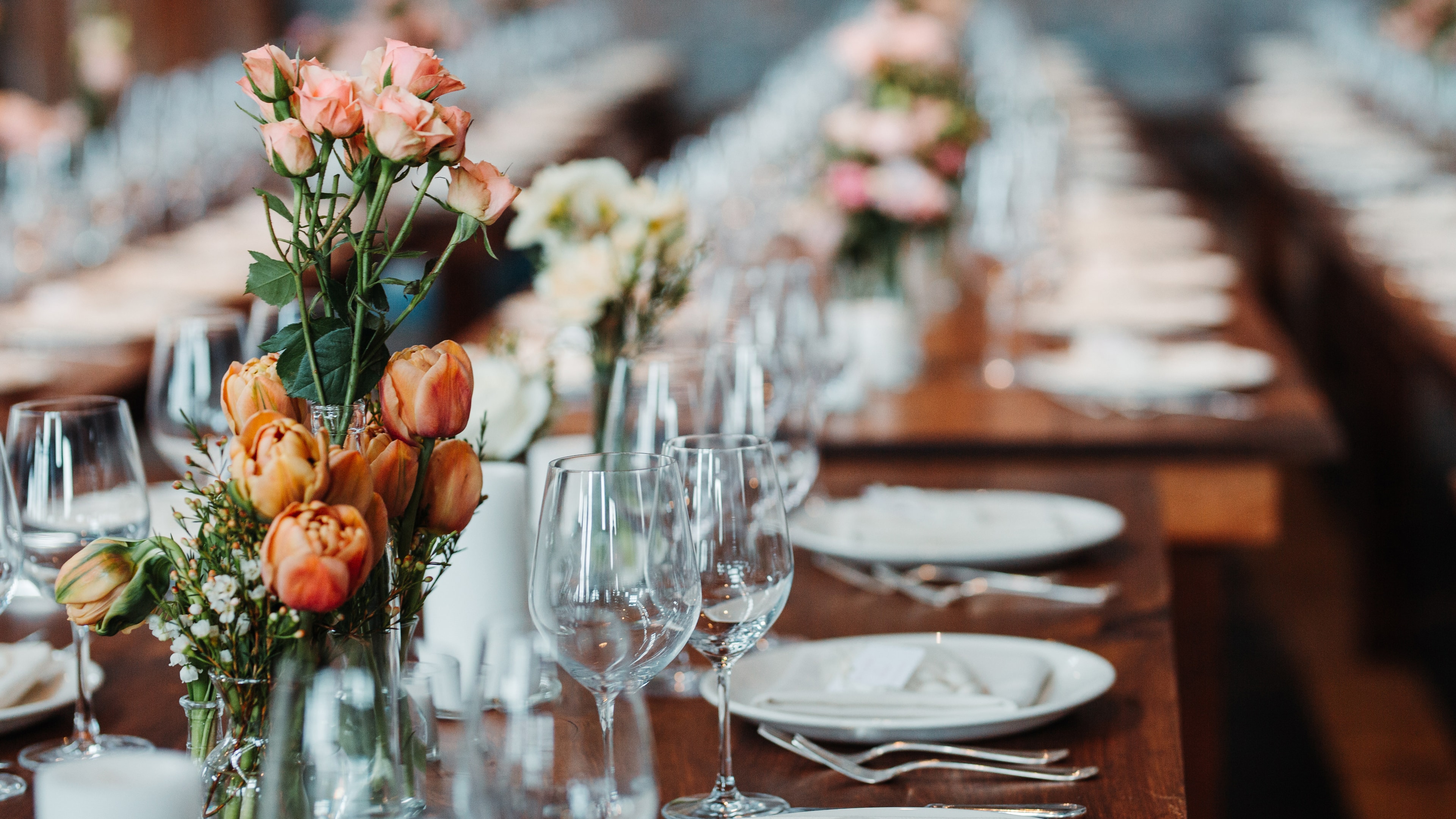 Tischgedeck mit Blumen auf langer Tafel.