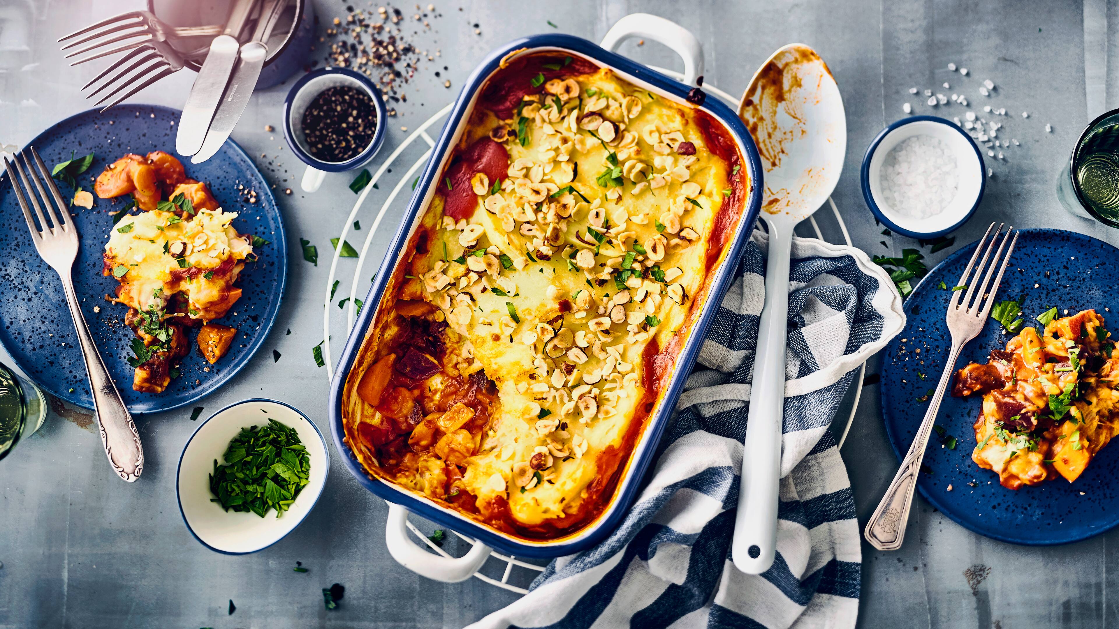 Rezept für einen bunten Gemüseauflauf mit Haselnuss-Püreehaube Eine Auflaufform mit Gemüse in Tomatensoße, überbackenen mit Käse, getoppt mit gehobelten Haselnüssen