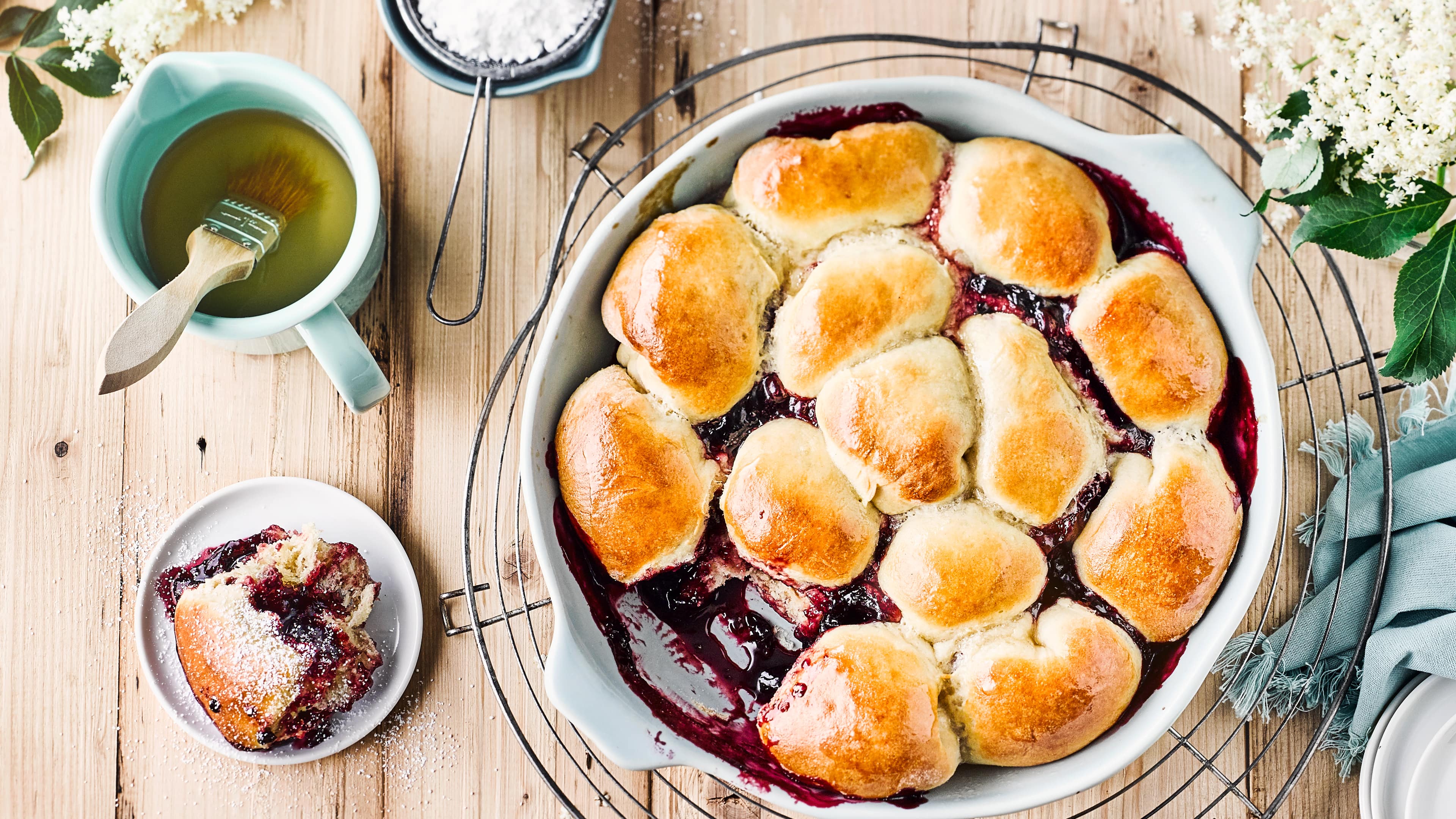 Holunder-Buchteln Probieren Sie unsere Variante dieser traditionellen Süßspeise aus Süddeutschland: Buchteln aus Hefe, Weizenmehl und Mandelmilch gefüllt mit Holunderblütengelee – fertig in 90 Minuten!