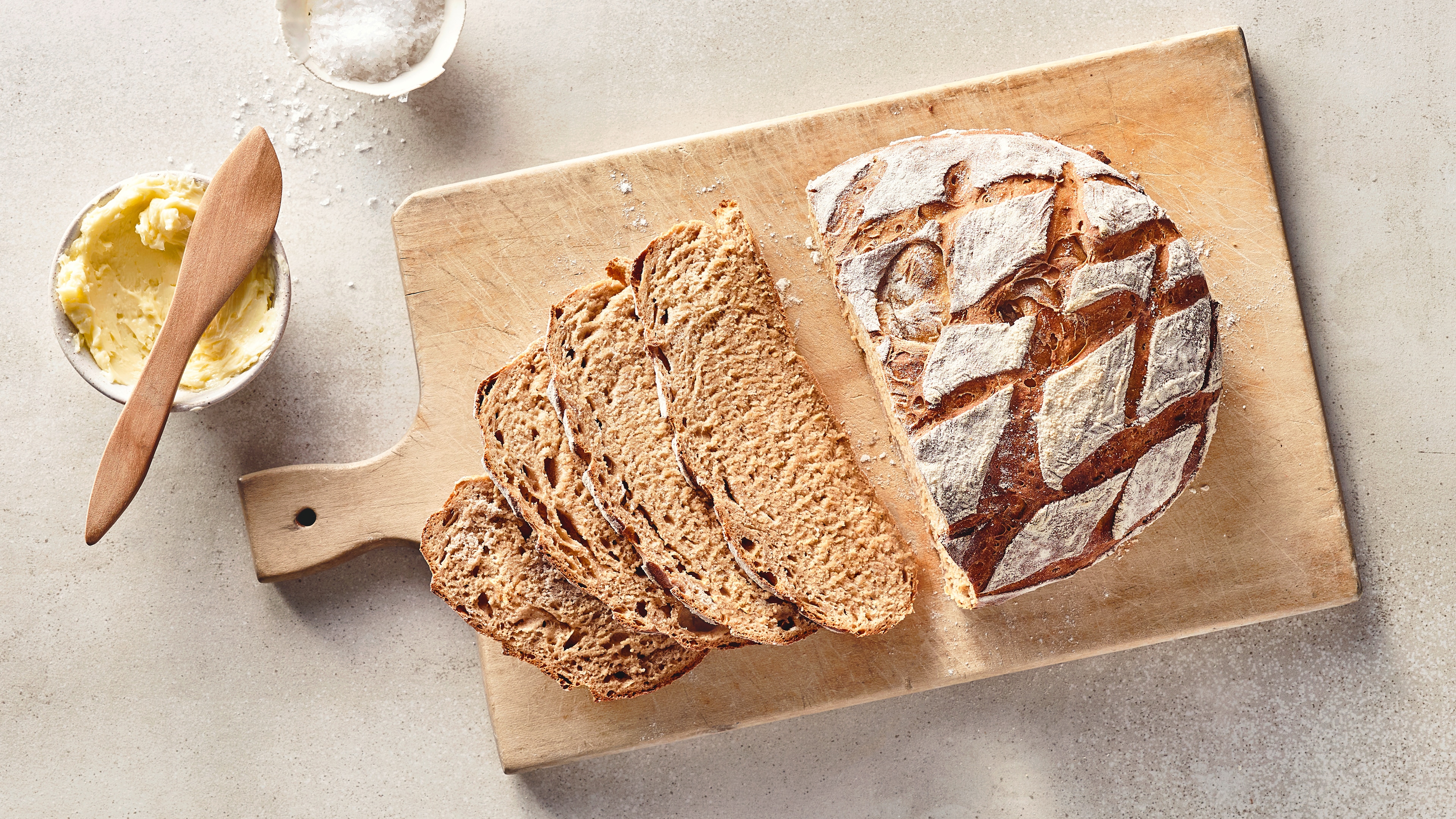 Brot-Rezept für Joghurtkruste Ein Leib Brot mit einem saftigen Teig und einer knusprigen Kruste mit einem rautenförmigen Muster, auf einem Holzbrett